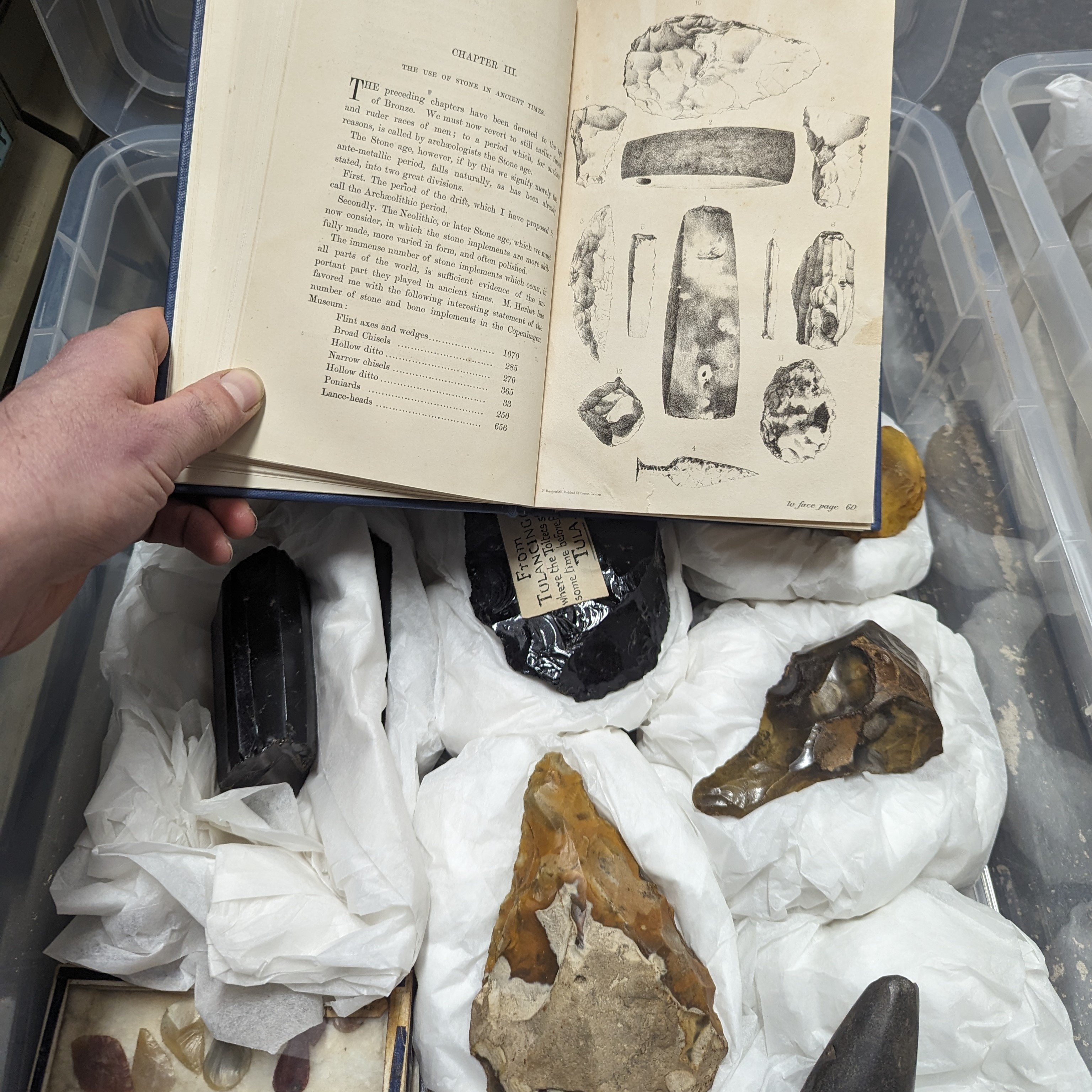 Lubbock's book 'Prehistoric Times' held with some prehistoric stone tools ready for an exhibition